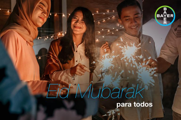Three people celebrate with sparklers. Text reads: "Eid Mubarak para todos" with a Bayer logo in the corner.