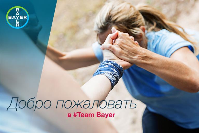 Two people clasp hands in a gesture of support. The Bayer logo is in the corner, with text in Russian saying "Welcome to #Team Bayer.