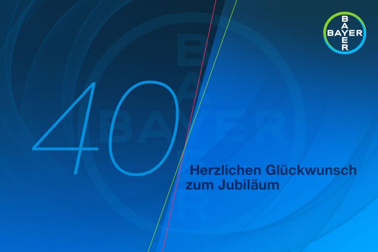 Blue graphic with "40" and Bayer logo. Text reads "Herzlichen Glückwunsch zum Jubiläum" in German, translating to "Congratulations on the Anniversary.