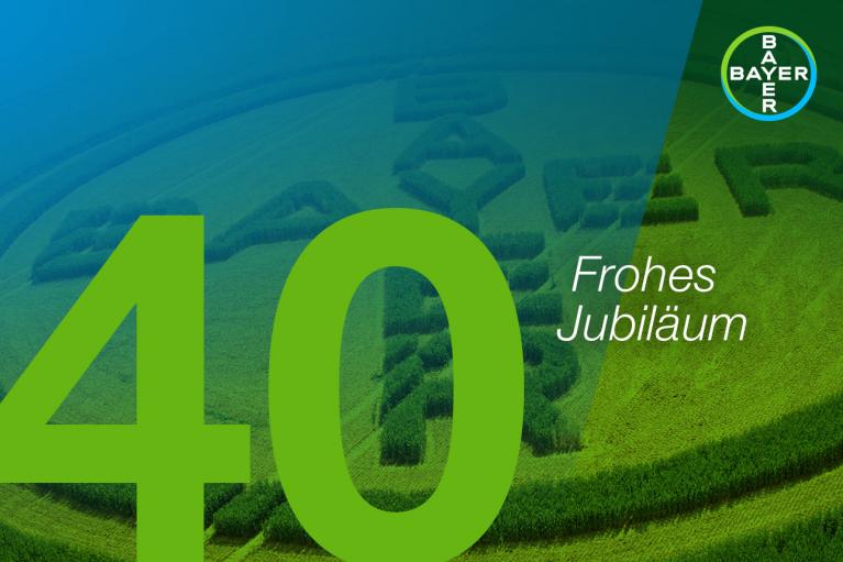 Large green "40" and "Frohes Jubiläum" text over an aerial view of a field with Bayer logo pattern. Bayer logo at the top right.