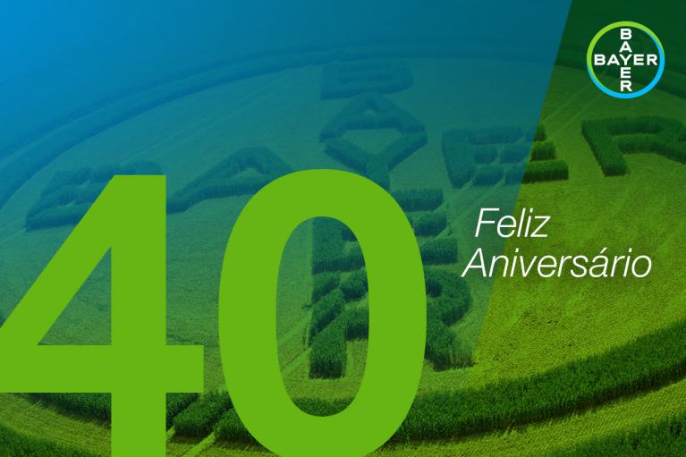 Green field with Bayer logo and "Feliz Aniversário" text, large green "40" in foreground, set against a blue gradient background.
