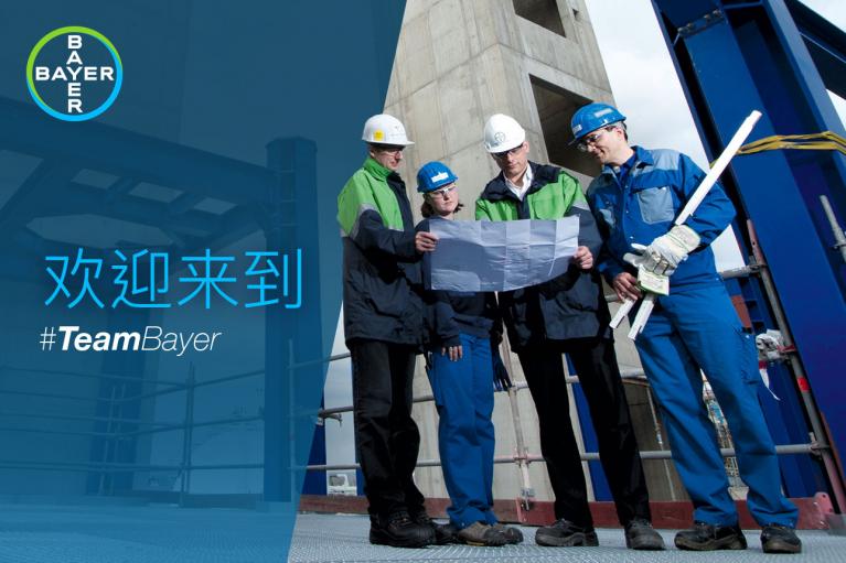 Four people in safety gear review a blueprint at a construction site, with a Bayer logo and Chinese text in the background.