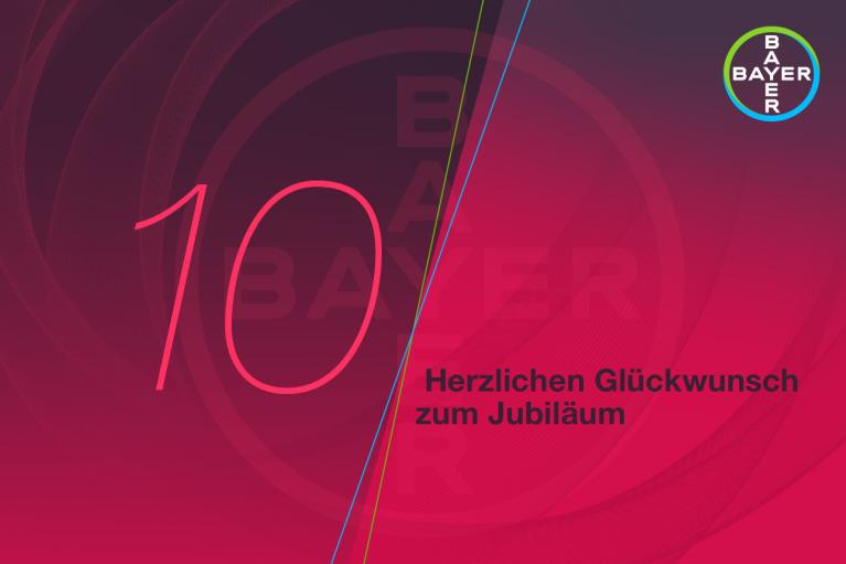 Graphic with the number 10 and "Herzlichen Glückwunsch zum Jubiläum" text in German. Bayer logo in the top right corner. Background features a red gradient design.