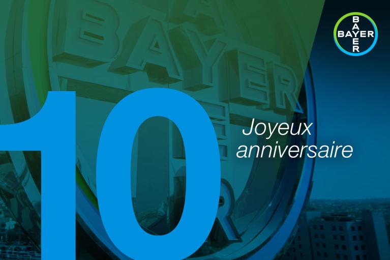 Large number 10 with "Joyeux anniversaire" text over a professional background featuring the Bayer logo.