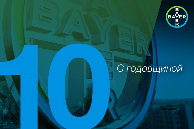 Blue number 10 and Russian text "С годовщиной" (With anniversary) over a background featuring the Bayer logo.