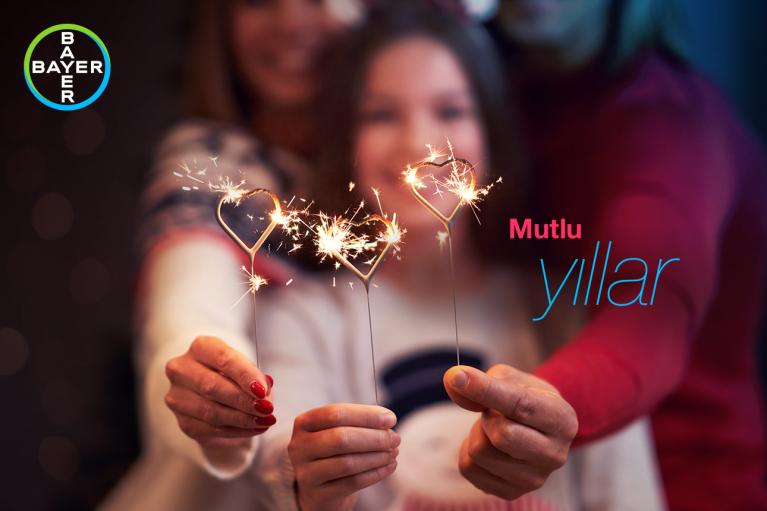 People holding heart-shaped sparklers with the words "Mutlu yıllar" and the Bayer logo visible in the image.
