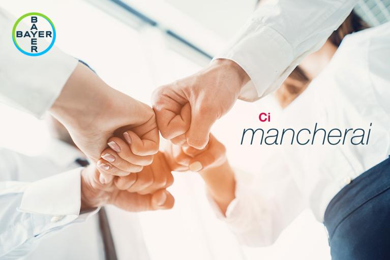 Four people in business attire fist bumping, with a Bayer logo in the corner and the text "Ci mancherai.