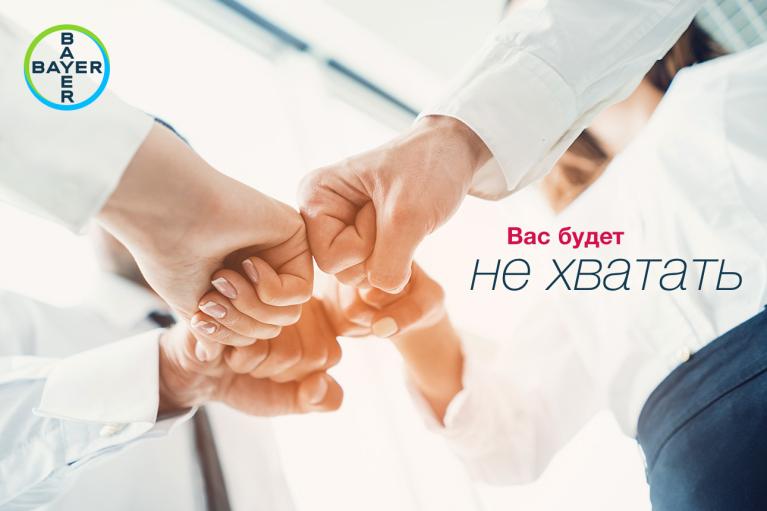 Four people in business attire join fists in a teamwork gesture. The Bayer logo is in the top left corner, with Russian text on the right.