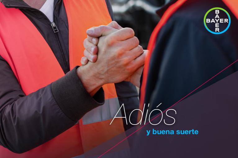 Two people wearing safety vests shake hands firmly. Overlay text in Spanish reads, "Adiós y buena suerte," with a circular logo in the top right corner.