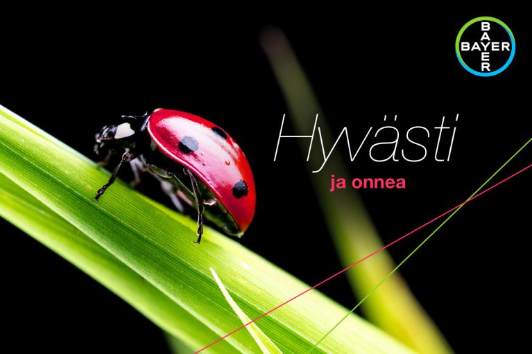 A ladybug on a green leaf with the words "Hyvästi ja onnea" and a Bayer logo in the top right corner.