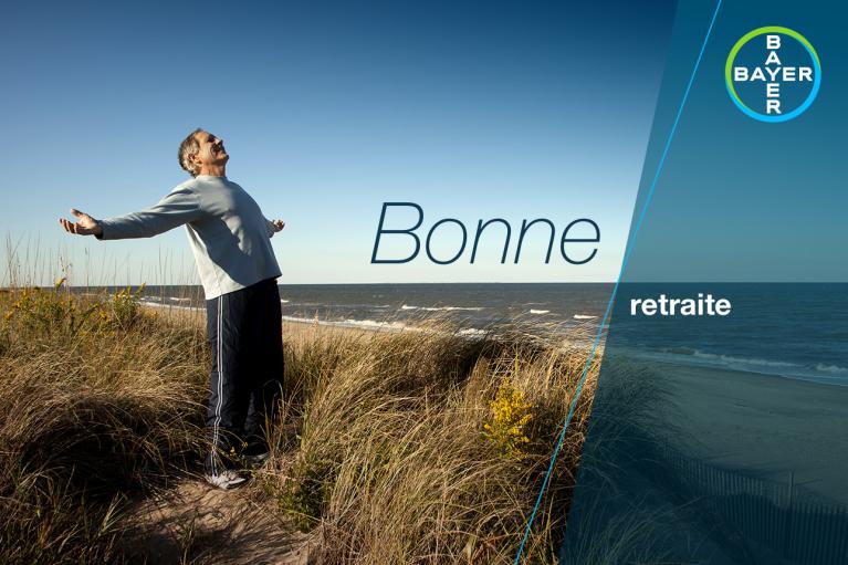 Person with arms outstretched stands in coastal grass by the sea, under a clear sky. Text reads "Bonne retraite" with Bayer logo in the corner.