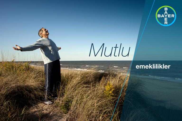Elderly person standing on a grassy dune by the sea, arms outstretched. "Mutlu" and "emeklilikler" text with Bayer logo in corner.