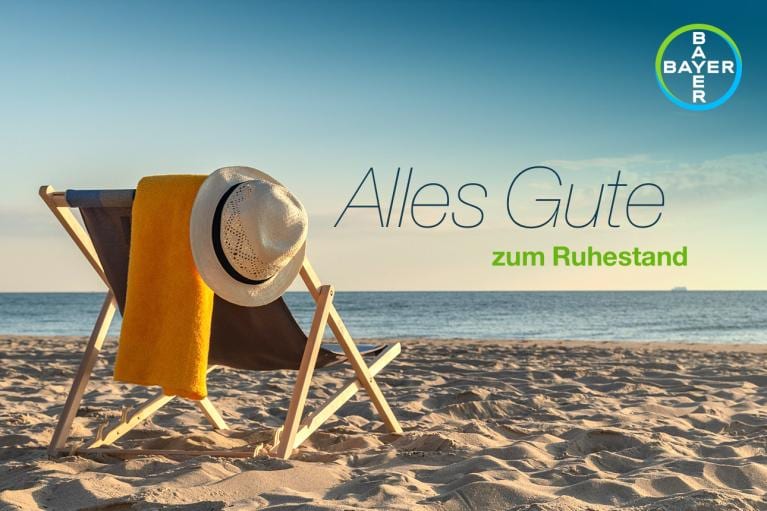 A beach scene with a chair, hat, and towel. The text reads "Alles Gute zum Ruhestand," with the Bayer logo in the corner.