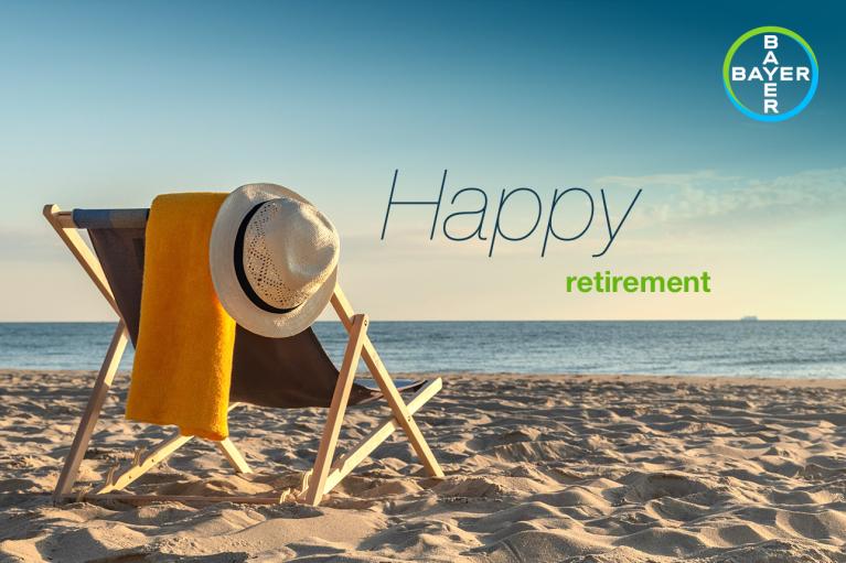A deck chair with a hat and towel sits on a sandy beach facing the sea. Text reads "Happy retirement." The Bayer logo is in the top right corner.