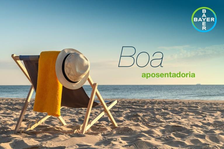 A beach chair and hat are on sandy shore with the ocean in the background. The words "Boa aposentadoria" and a Bayer logo are visible.