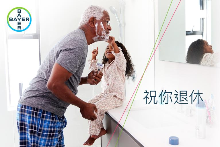 A man and a child are in a bathroom; the man is shaving and the child is smiling and pointing. There are Chinese characters and a Bayer logo in the image.