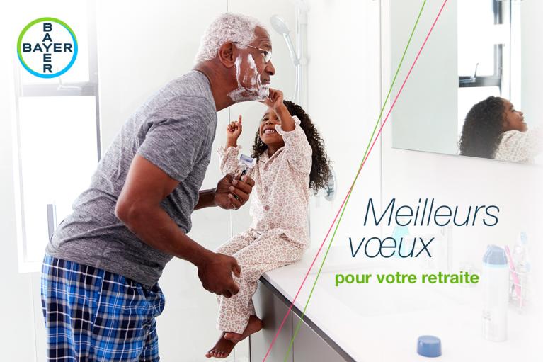 An elderly man shaving with a young girl in pajamas playing with shaving foam in a bathroom. Text reads, "Meilleurs voeux pour votre retraite" with the Bayer logo.