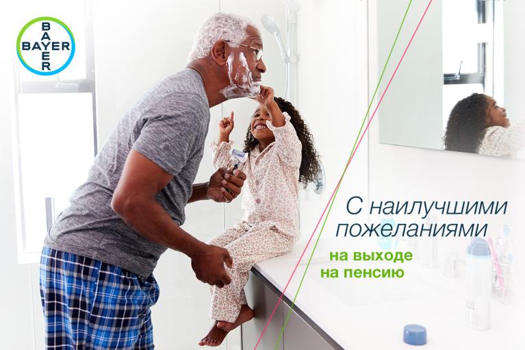 A man shaving in the bathroom with a young girl playfully holding shaving cream. Russian text overlay reads: "С наилучшими пожеланиями на выходе на пенсию," with Bayer logo in the corner.