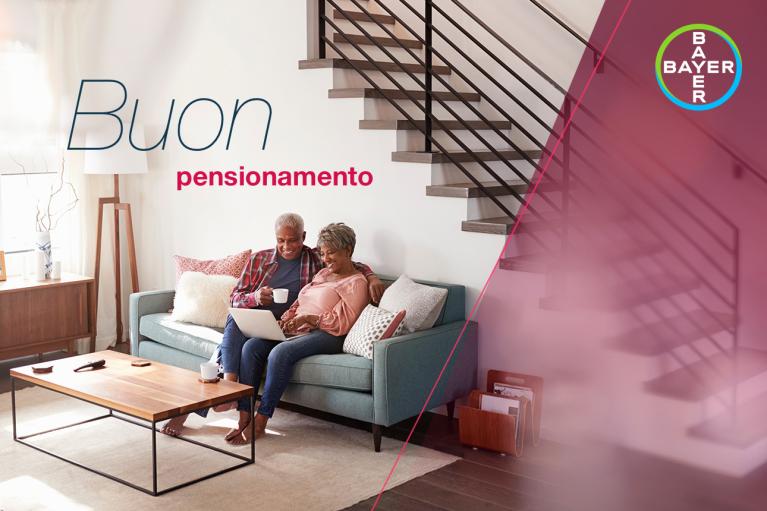 An older couple sits on a sofa, smiling and using a laptop. Italian text reads "Buon pensionamento." The Bayer logo is in the corner.