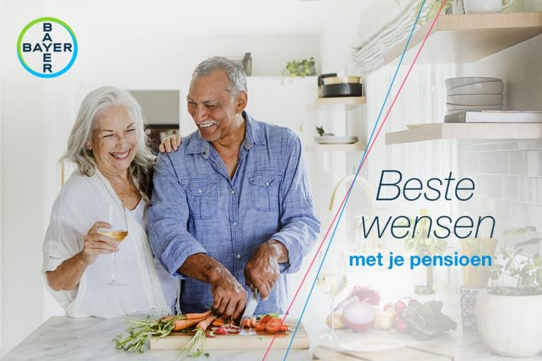 An elderly couple smiles while preparing food in a kitchen, with the Bayer logo and the text "Beste wensen met je pensioen" on the right side.