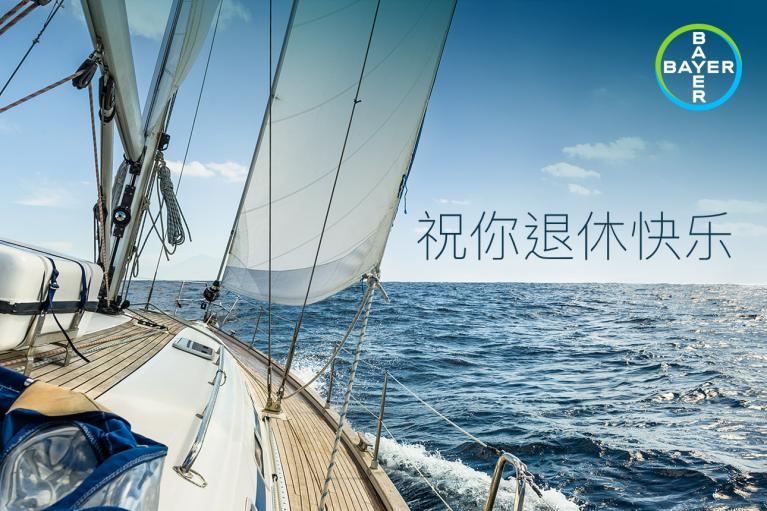 Sailboat on open sea with clear skies. Chinese text and Bayer logo in the corner.