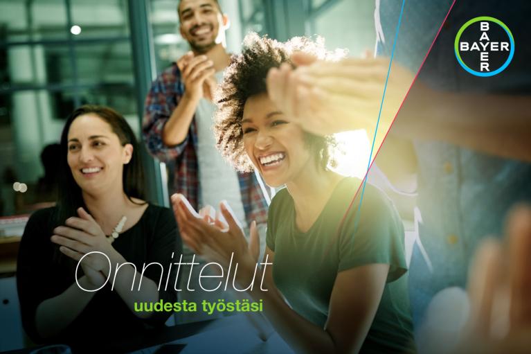 A group of people clapping and smiling, with the words "Onnittelut uudesta työstäsi" overlaid. Bayer logo is visible in the top right corner.