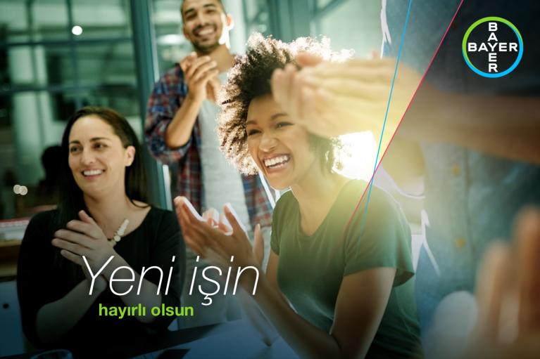 Group of people smiling and clapping in celebration. Text reads, "Yeni işin, hayırlı olsun." Bayer logo in top right corner.