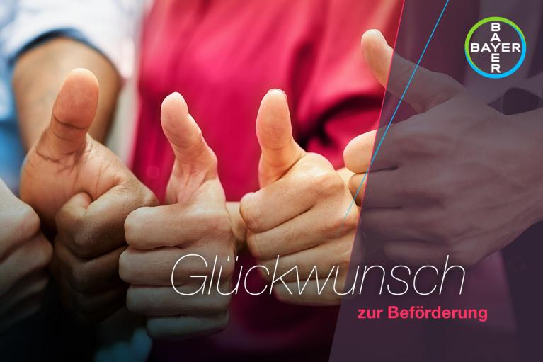Several people giving thumbs up; text in German reads "Glückwunsch zur Beförderung" with Bayer logo in the corner.
