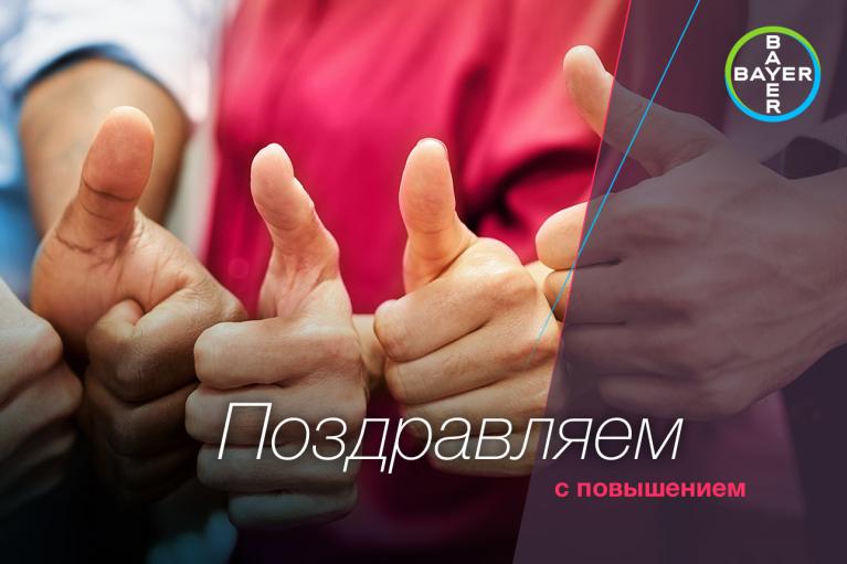 Close-up of several people giving thumbs up, with a Bayer logo and Russian text congratulating on a promotion.