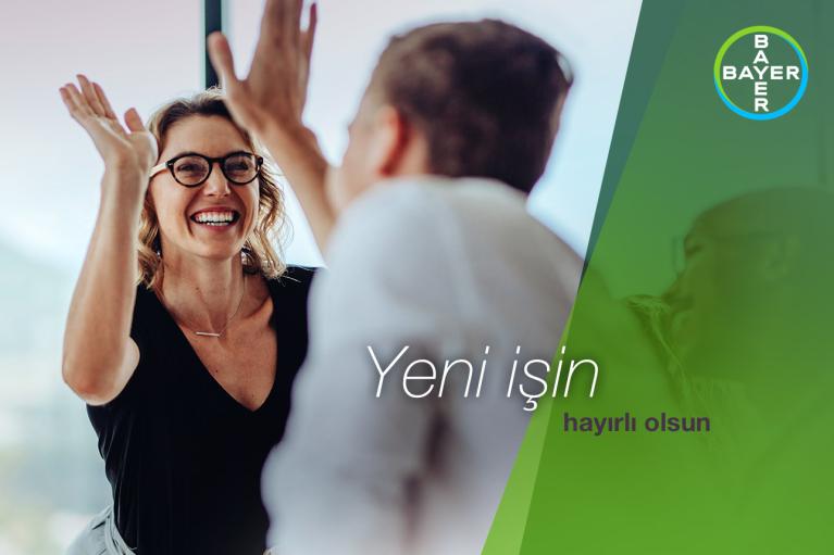Two people high-fiving with a blurred background. Text reads, "Yeni işin hayırlı olsun." Bayer logo on a green and blue gradient on the right.