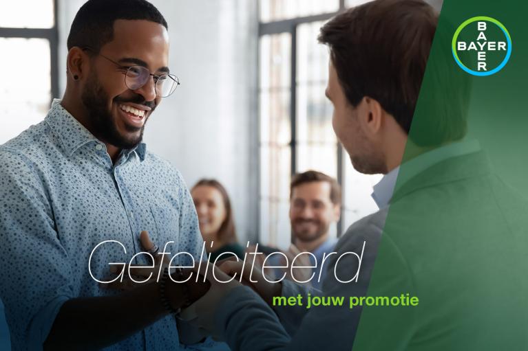 A group of people in an office setting, with two men shaking hands. Dutch text reads "Gefeliciteerd met jouw promotie." Bayer logo is in the top right corner.