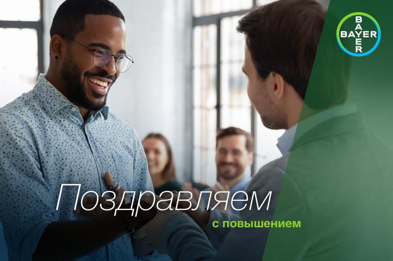 A man is congratulating another man in an office setting. The words "Поздравляем с повышением" and the Bayer logo are visible.