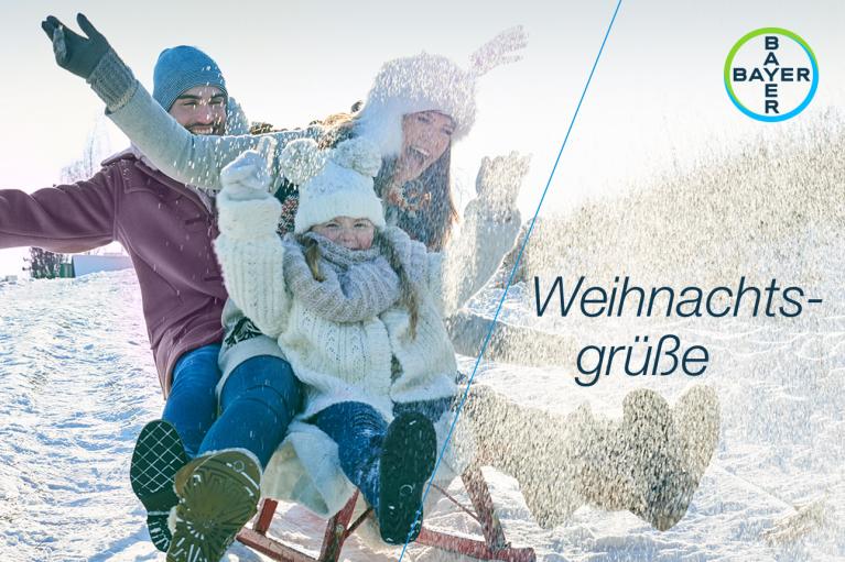 Weihnachtsgrüße, Father, mother and child on a sled in the snow