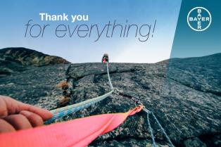 A person climbs a rock face using ropes, with a "Thank you for everything!" message and Bayer logo in the corner.