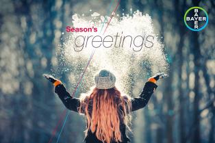 Person in winter clothing throws snow in the air with "Season's Greetings" text and Bayer logo visible.