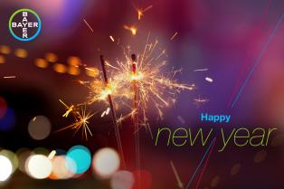Sparklers with colorful bokeh lights in the background. Text reads "Happy New Year" with the Bayer logo in the corner.
