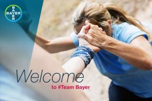 Two people clasp hands in support, one wearing a blue shirt and the other a blue bandana, with "Welcome to #Team Bayer" text displayed.