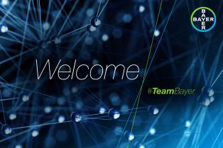 Abstract network design with connected spheres and lines, featuring the words "Welcome" and "#TeamBayer" in front of a dark blue background. Logo of Bayer in the top right corner.