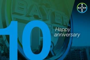 Blue and green graphic with large number 10, "Happy anniversary" text, and Bayer logo in the top right corner.
