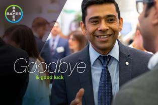 A man in a suit smiles while engaging in conversation at a social event. The image includes the words "Goodbye & good luck" and the Bayer logo.